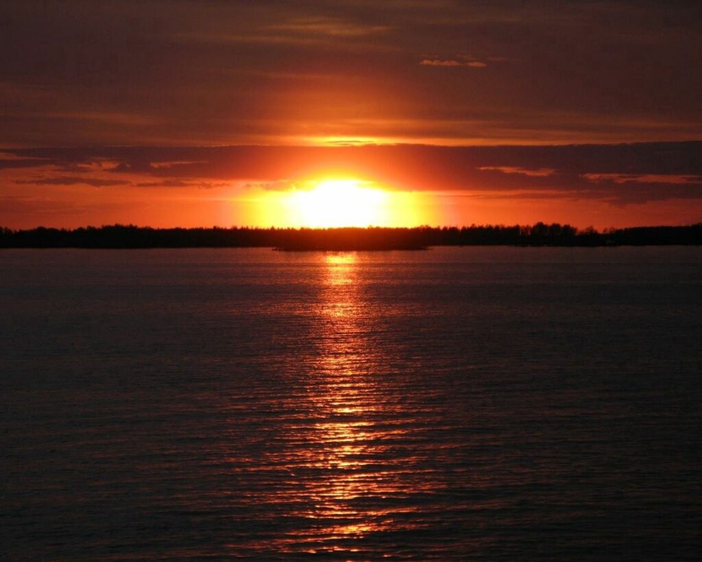 Sunset wallpaper with orange and gold hues reflecting on calm water creating tranquil scene