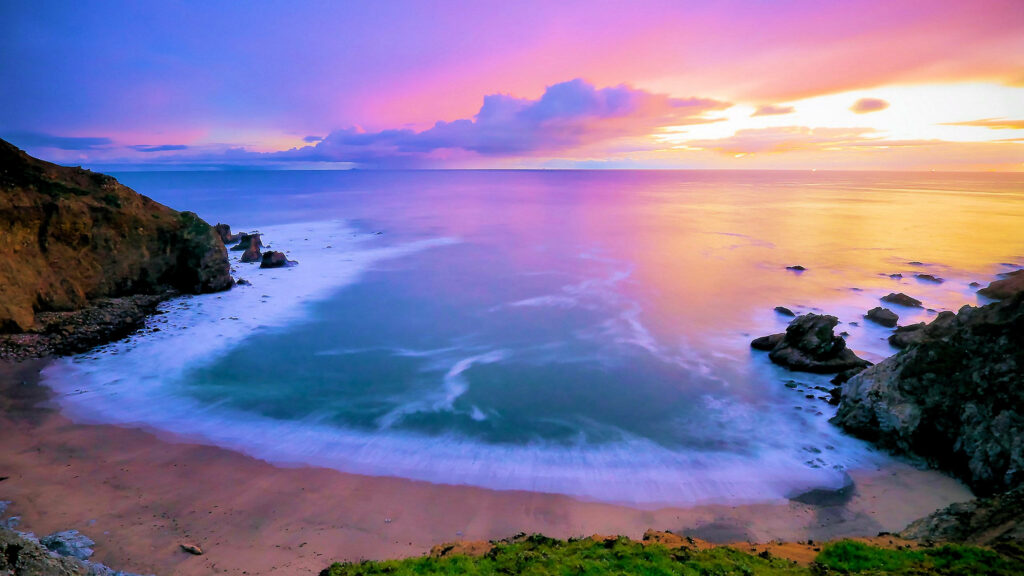 A Stunning 2560 X 1440 Sunset Wallpaper of a Beach Enclosed by the Sea