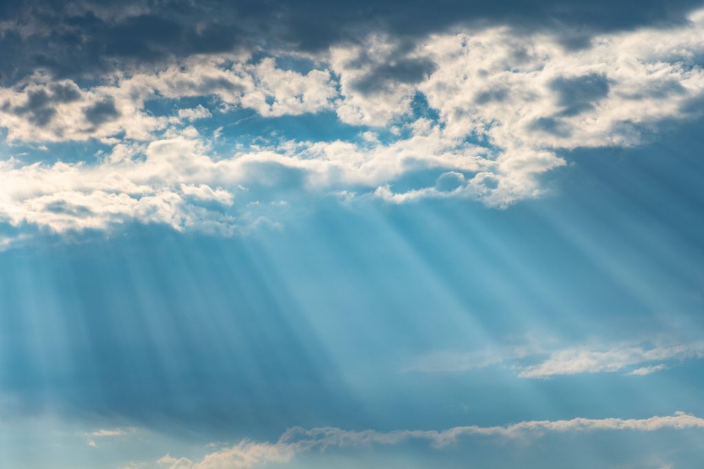 Sunshine wallpaper with blue sky and crepuscular rays streaming through fluffy clouds serene nature