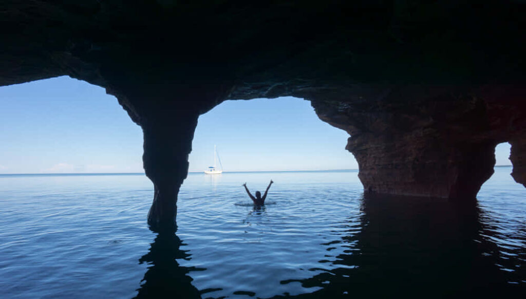 Serene Swim Scene: Calm Waters & Rock Archway Background Wallpaper