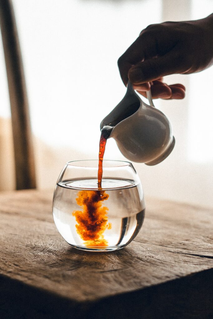 Serene Tea Pour: Swirling Water Art on Wooden Wallpaper Background