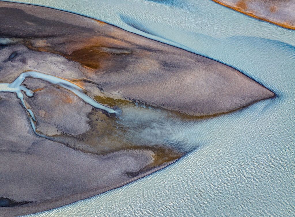 Top view of island with winding river showcasing natural relief patterns in earthy colors Wallpaper