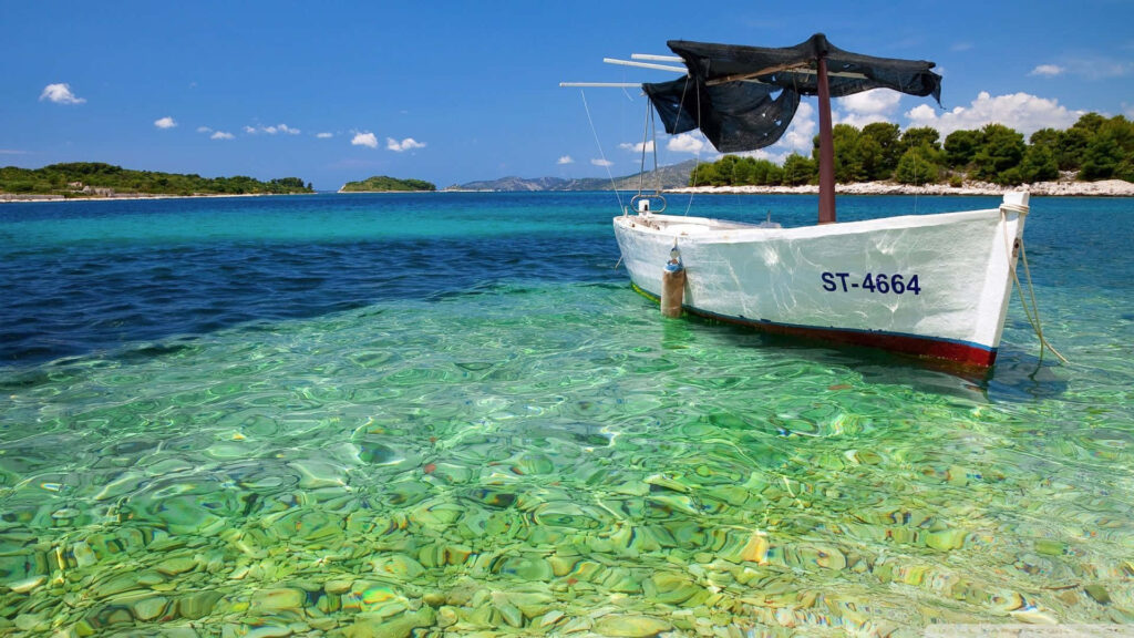 Tropical Beach Paradise: Serene Wallpaper with Boat & Lush Islands
