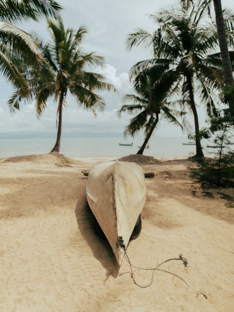 Serene beach wallpaper with weathered boat on golden sand palm trees and calm sea horizon