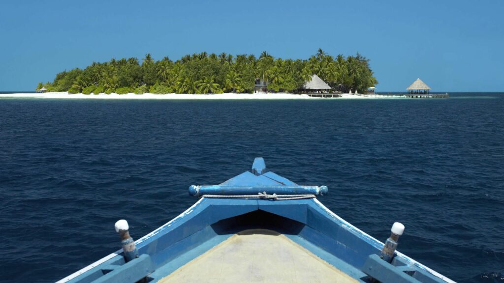 Serene boat ride on deep blue ocean toward tropical island with palm trees and sandy beaches Wallpaper