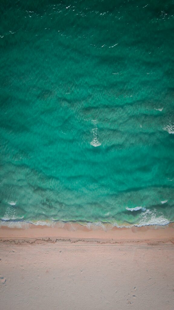 Aerial view of turquoise ocean waves meeting soft sandy shore calm peaceful seascape wallpaper
