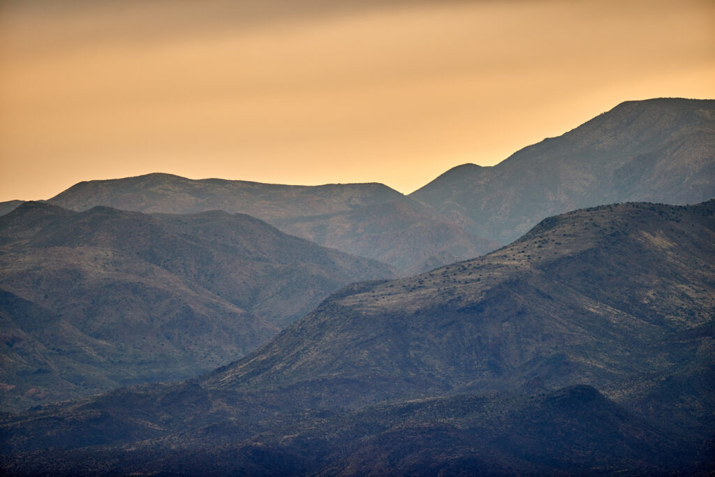 Serene mountain landscape at twilight with pastel sky and layered rugged terrain wallpaper background