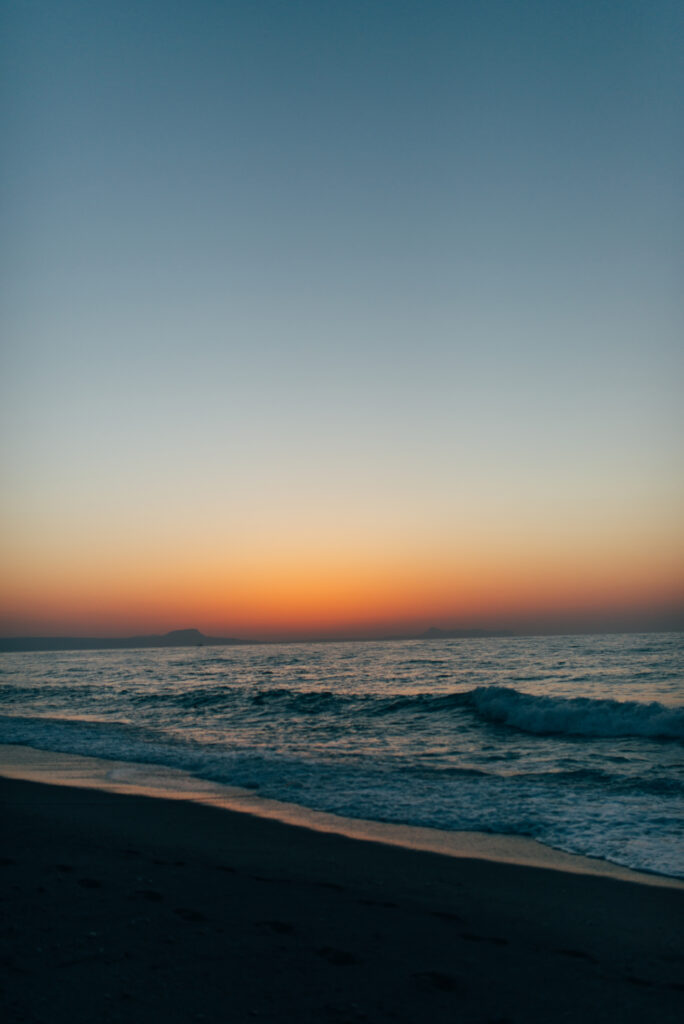 Serene twilight shore with gentle waves reflecting orange and blue sky over calm sea wallpaper