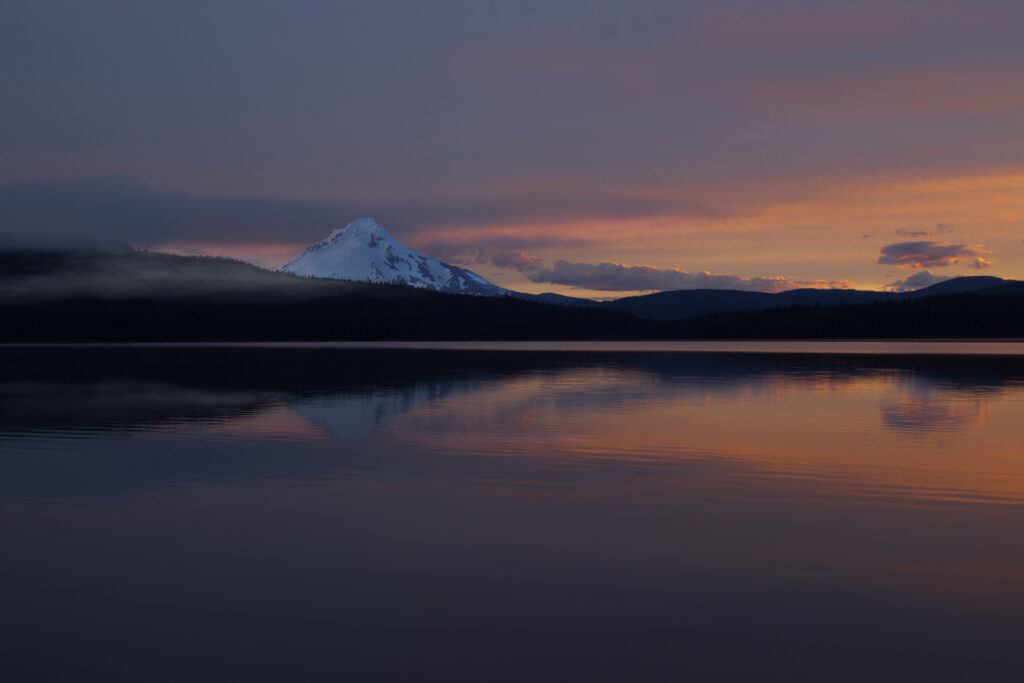 Snow-capped mountain and rolling hills reflected on calm lake at twilight with colorful sky Wallpaper