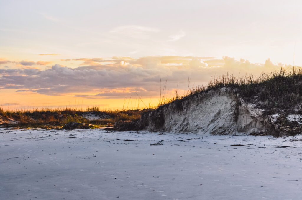 Twilight snowy field with grass patches on sandy dunes warm sunset hues serene landscape wallpaper