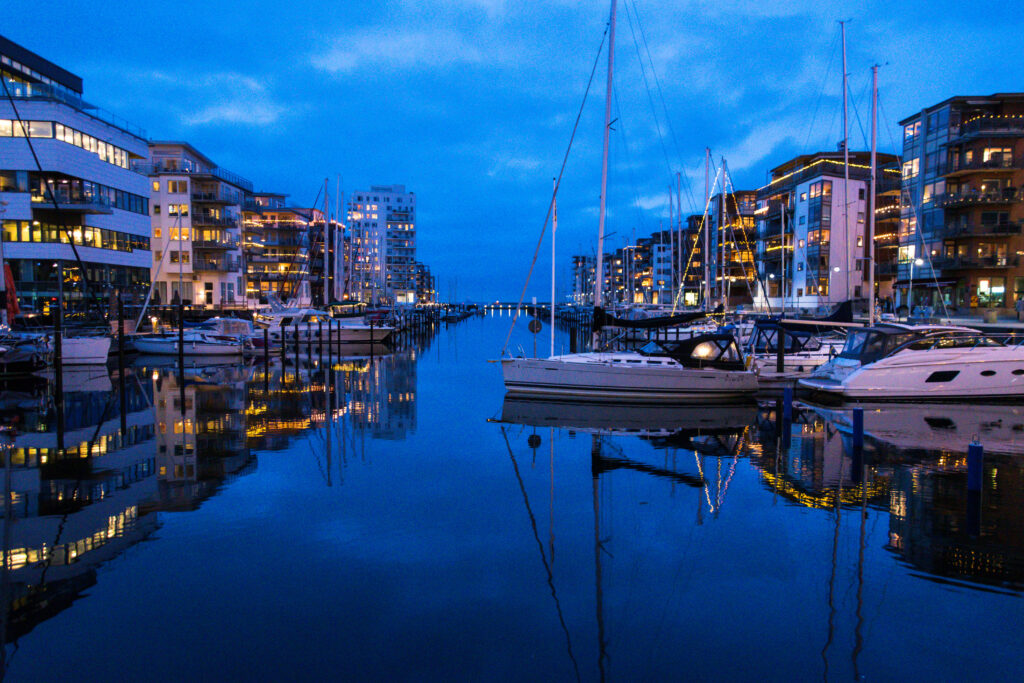 Twilight Urban Waterfront Wallpaper: Serene River with Docked Sailboats