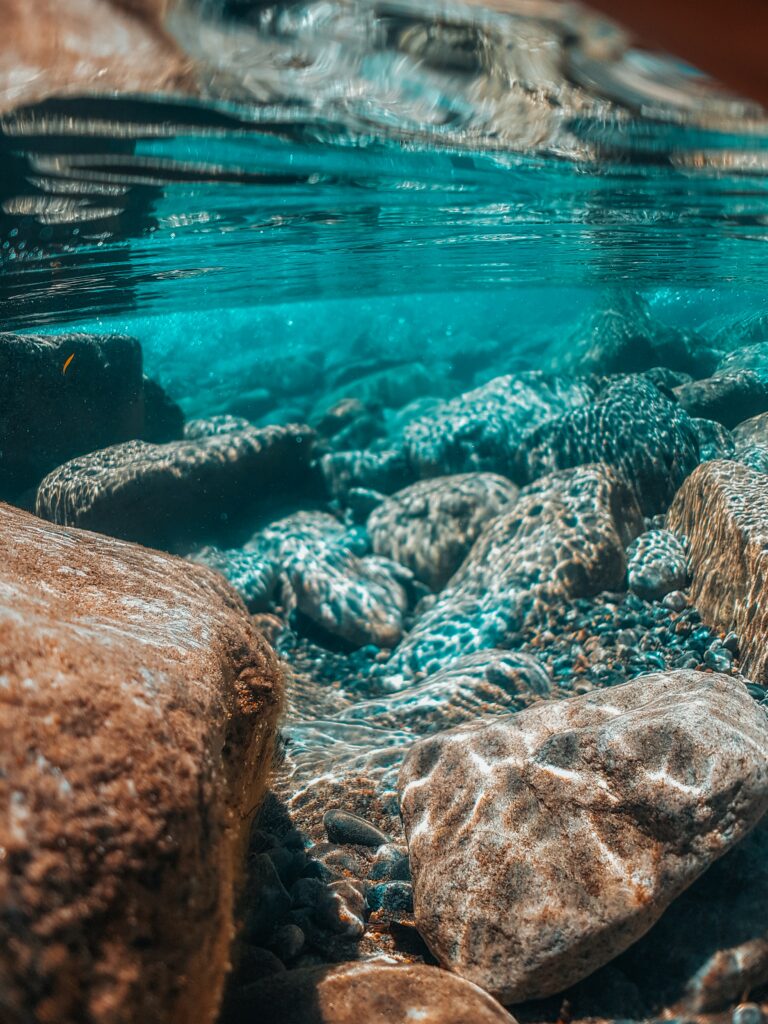 Serene underwater scene with turquoise water and smooth stones reflecting light calm wallpaper