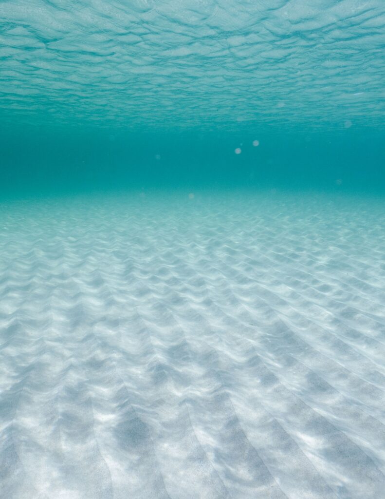 Serene underwater wallpaper with gentle sand ripples and clear deep blue water background