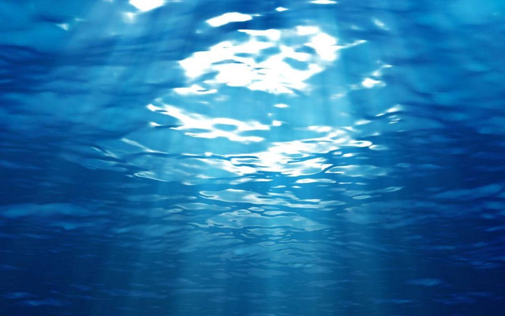 Serene underwater scene with sunlight rays and caustic light patterns on deep blue ocean surface Wallpaper
