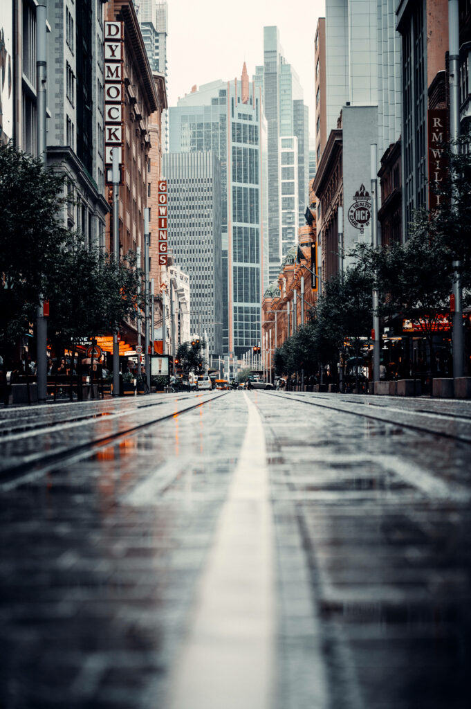 Serene Cityscape Wallpaper: Wet Road Reflecting Vibrant Urban Life