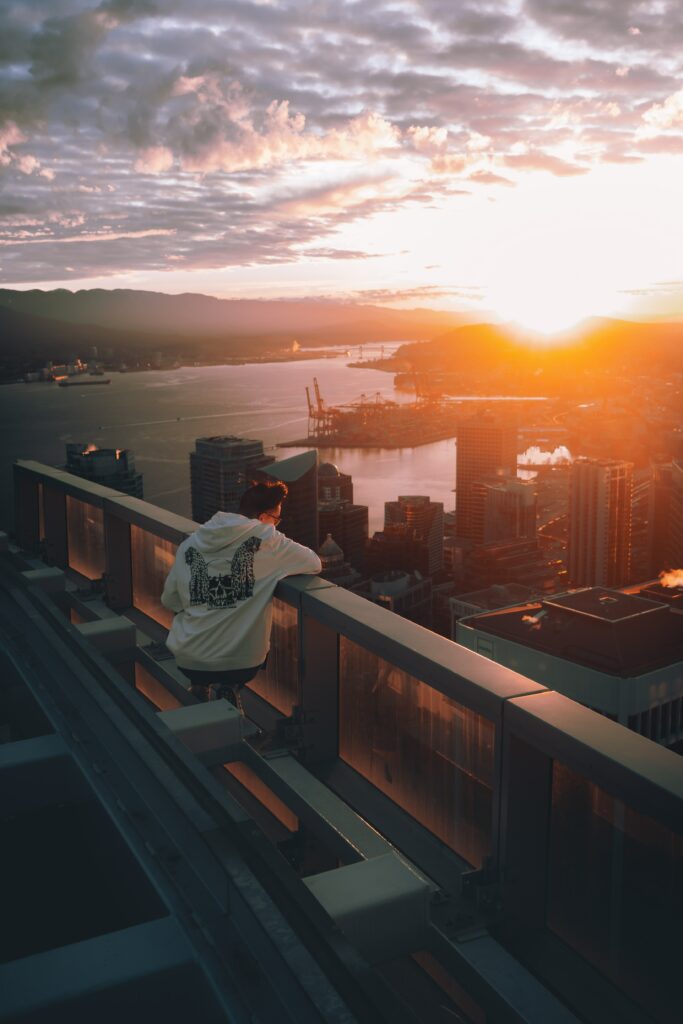 Serene Rooftop Sunset Wallpaper: Lone Man Overlooking Cityscape
