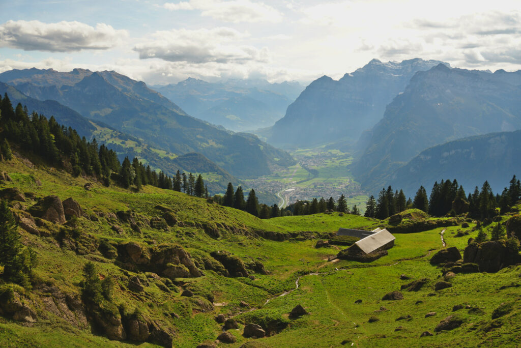 Tranquil valley wallpaper with lush green fields quaint hillside house and distant mountains view