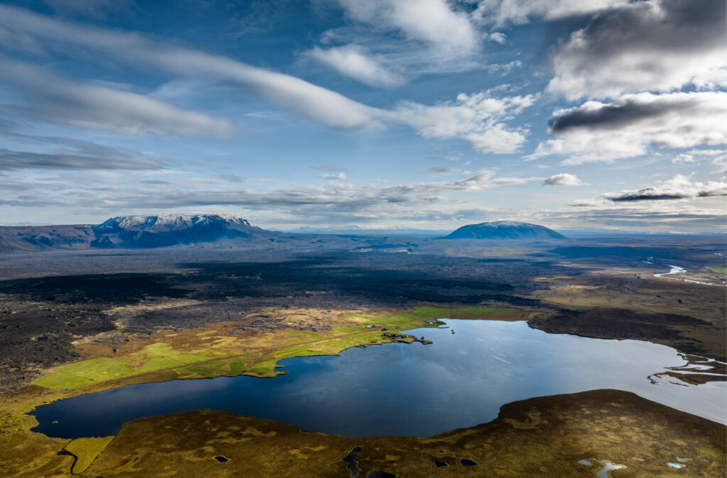 Breathtaking valley with serene pond reflecting dramatic sky and majestic mountains background Wallpaper