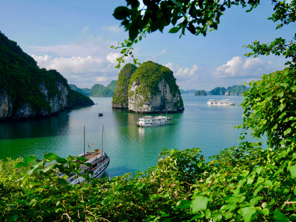 Serene Vietnam bay wallpaper with emerald waters limestone rocks lush greenery and elegant ships