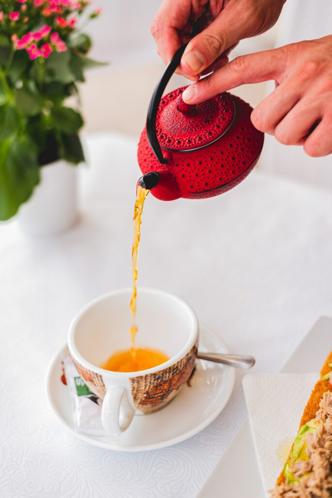Serene Tea Time Wallpaper: Hands Pouring from a Red Kettle