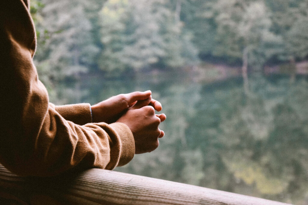 Serene Wallpaper: Hands on Railing with Lush Forest & Calm Lake