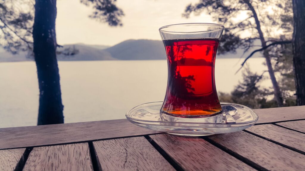 Serene Tea Wallpaper: Glass on Wooden Table by Peaceful Lake