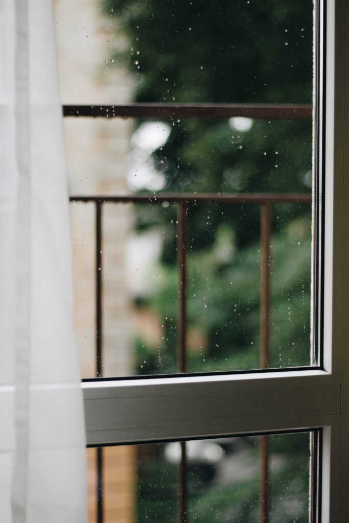 Serene Glass Window Wallpaper with Water Droplets and Greenery