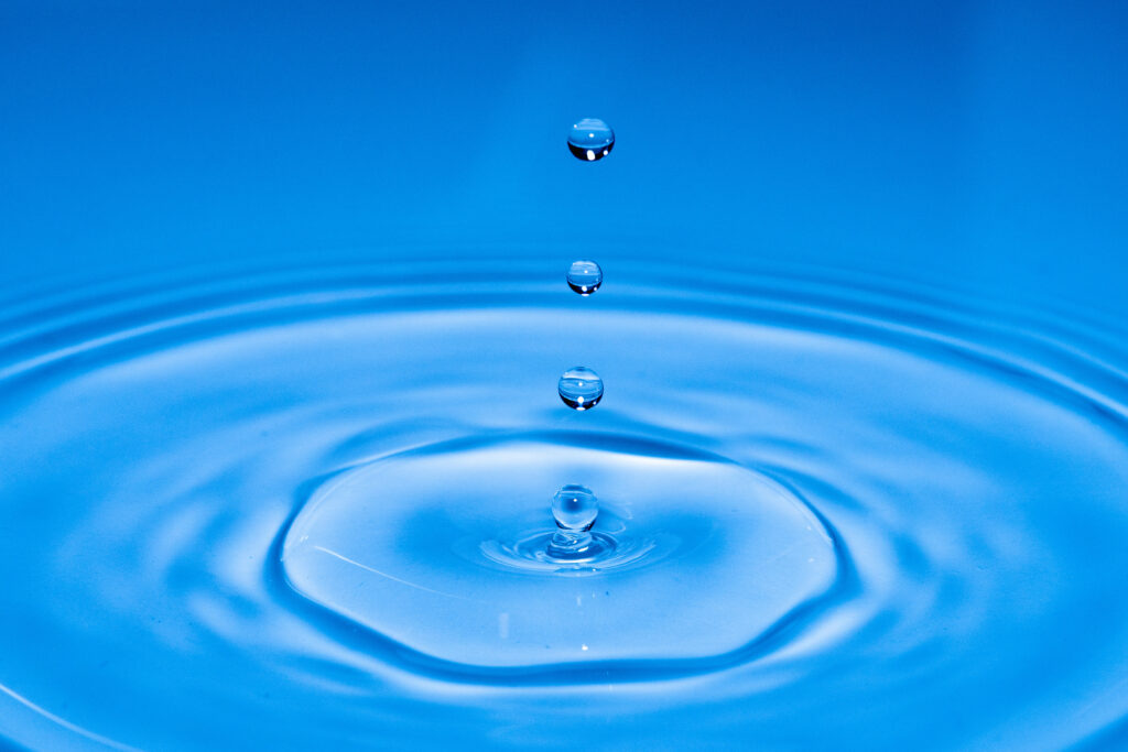 Serene Water Droplets Wallpaper: Tranquil Ripples on Blue Background