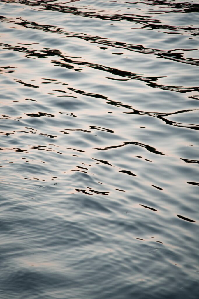 Calm water wallpaper with gentle ripples soft waves and shimmering blue reflective highlights