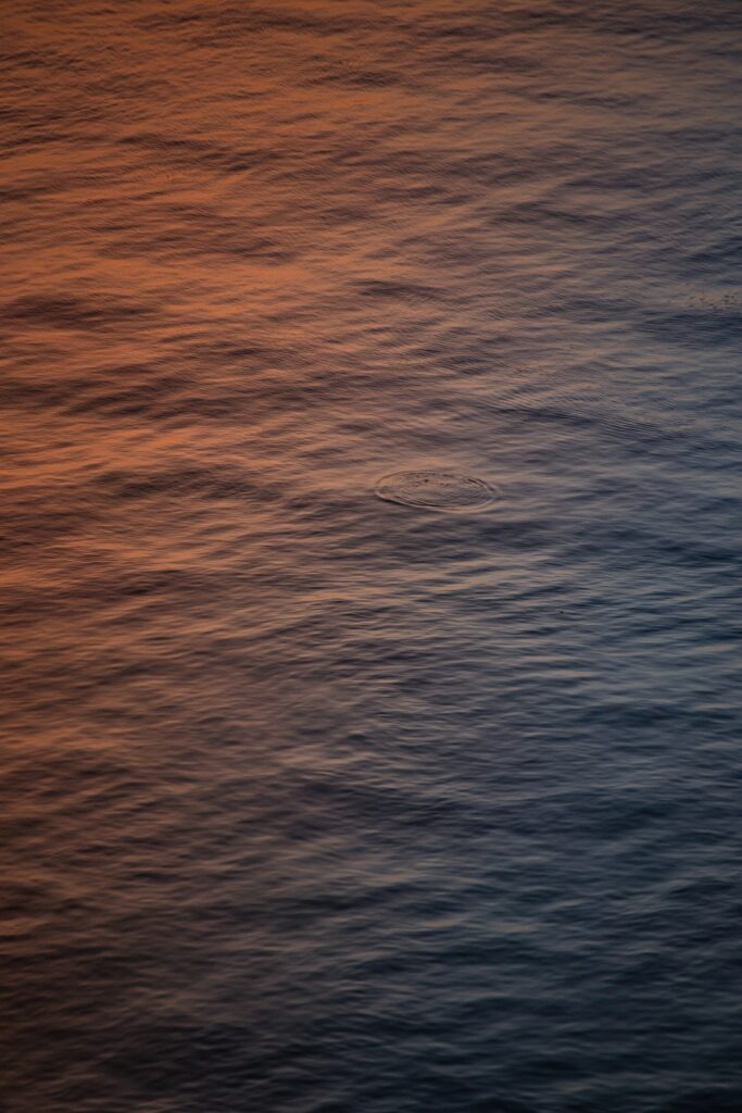 Serene water ripples with warm orange and cool blue hues creating a peaceful minimalist wallpaper background