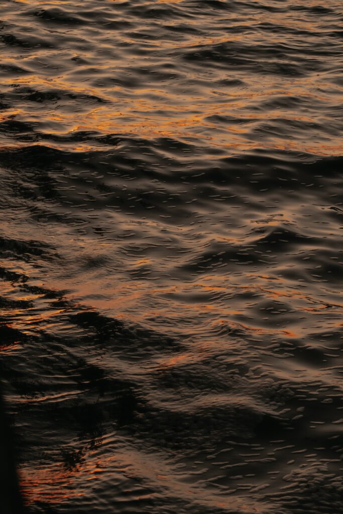 Serene water wallpaper with gentle waves and warm orange reflections creating calm ripples