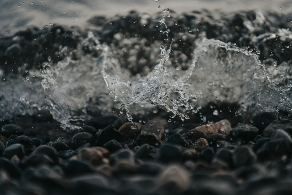 Serene Wallpaper: Water Splashing on Smooth Stones & Pebbles