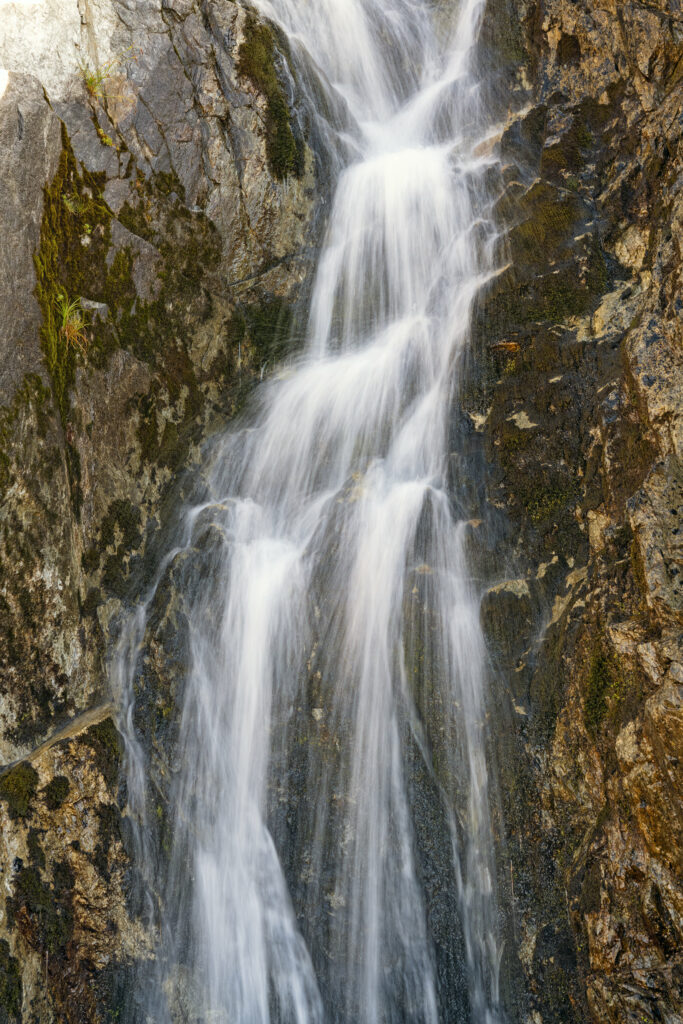 Waterfall cascading over rugged rocks with smooth streams creating a serene natural scene Wallpaper