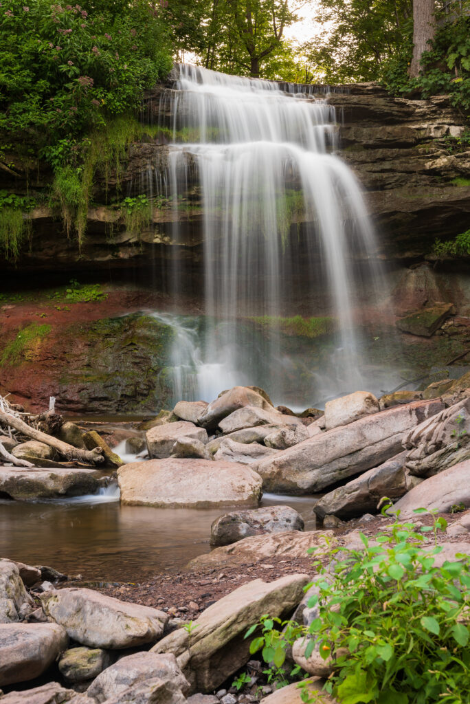 Serene waterfall cascading over rocks with lush greenery and misty peaceful nature landscape wallpaper