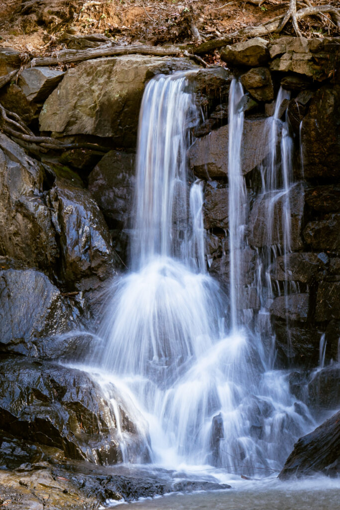 Serene waterfall cascading over dark wet stones with mist and splashes nature wallpaper background