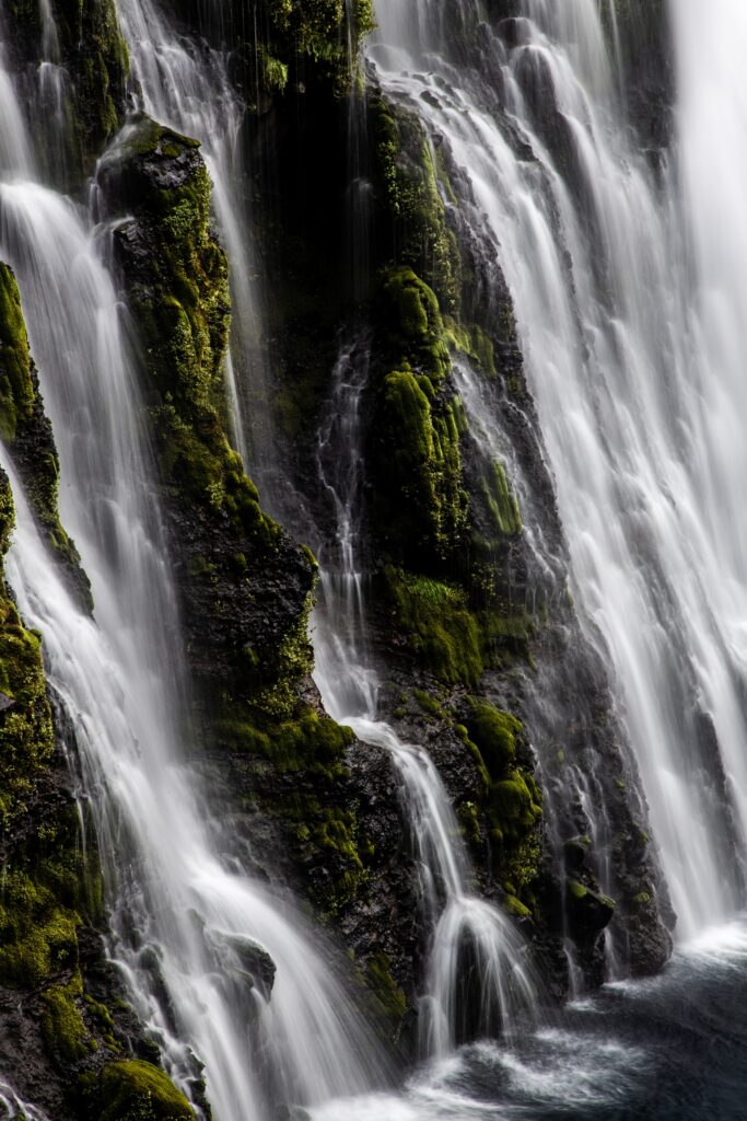 Waterfall cascading over mossy rocks in a serene natural landscape wallpaper background