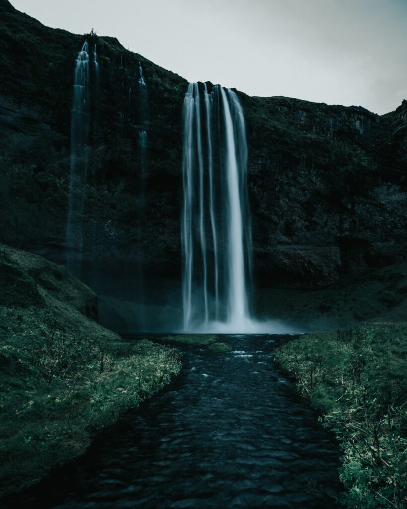 Waterfall cascading over rocks into calm water surrounded by lush green forest landscape wallpaper