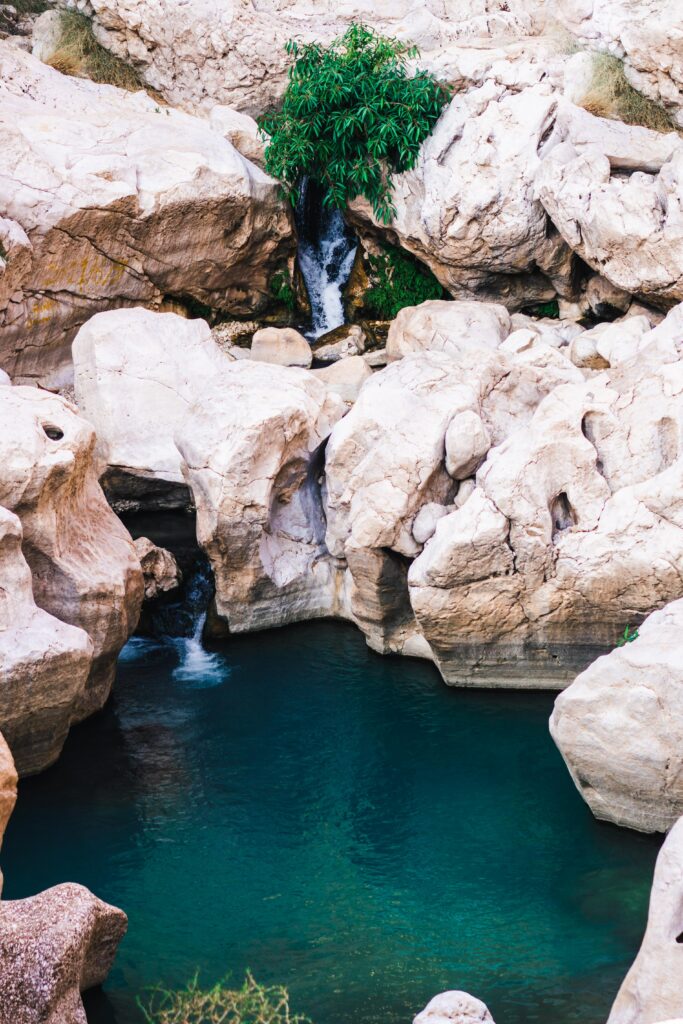 Tranquil waterfall with smooth pale rocks and vibrant green plants by clear blue stream wallpaper