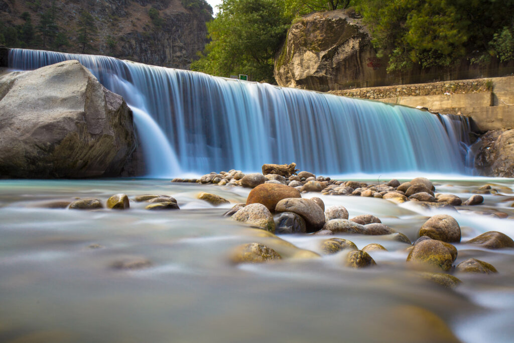 Serene waterfall cascading over rocks with misty fog lush green trees and peaceful nature scene Wallpaper