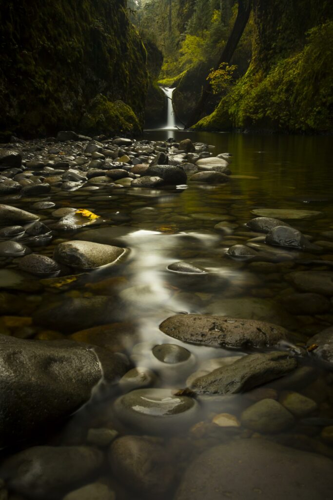 Serene waterfall with silky flow over smooth stones moss and lush green forest background wallpaper