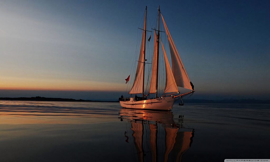 White sailing boat gliding on calm water at sunset with glowing sails and peaceful reflection Wallpaper