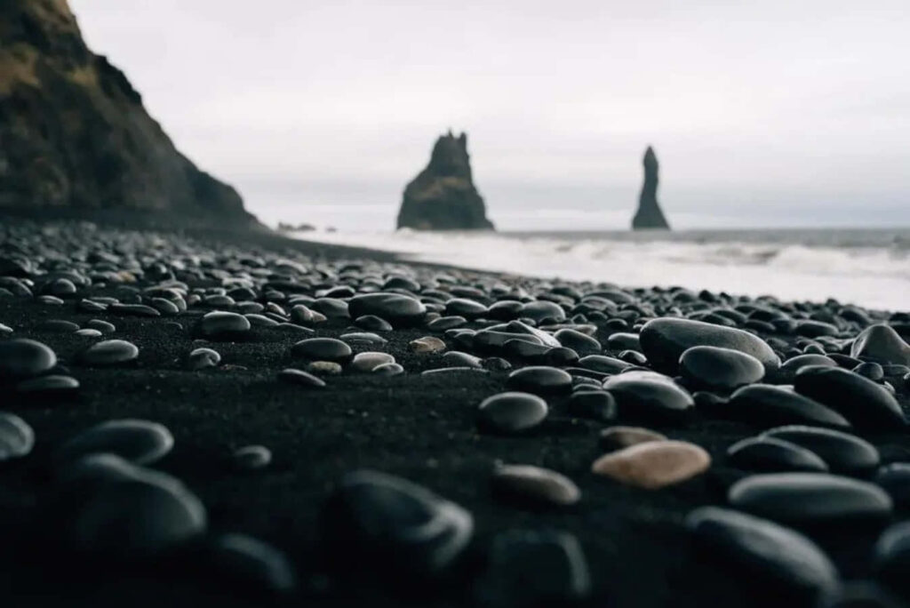 Stunning Pebbles on Black Sand Beach: Serene Wilderness Background Wallpaper