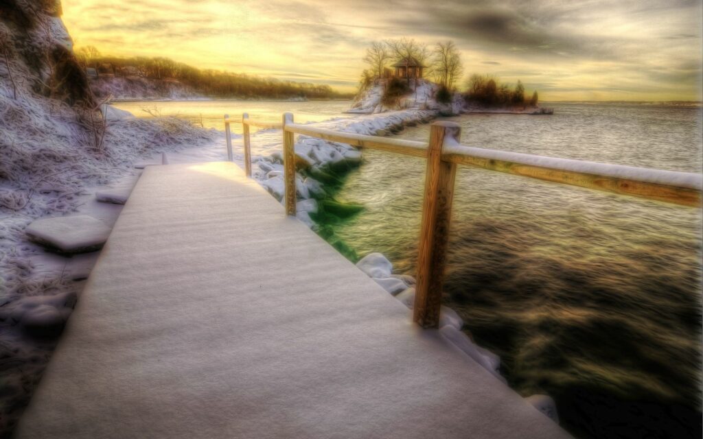 Winter wooden bridge snow covered handrail peaceful coastline calm sea golden sunlight wallpaper