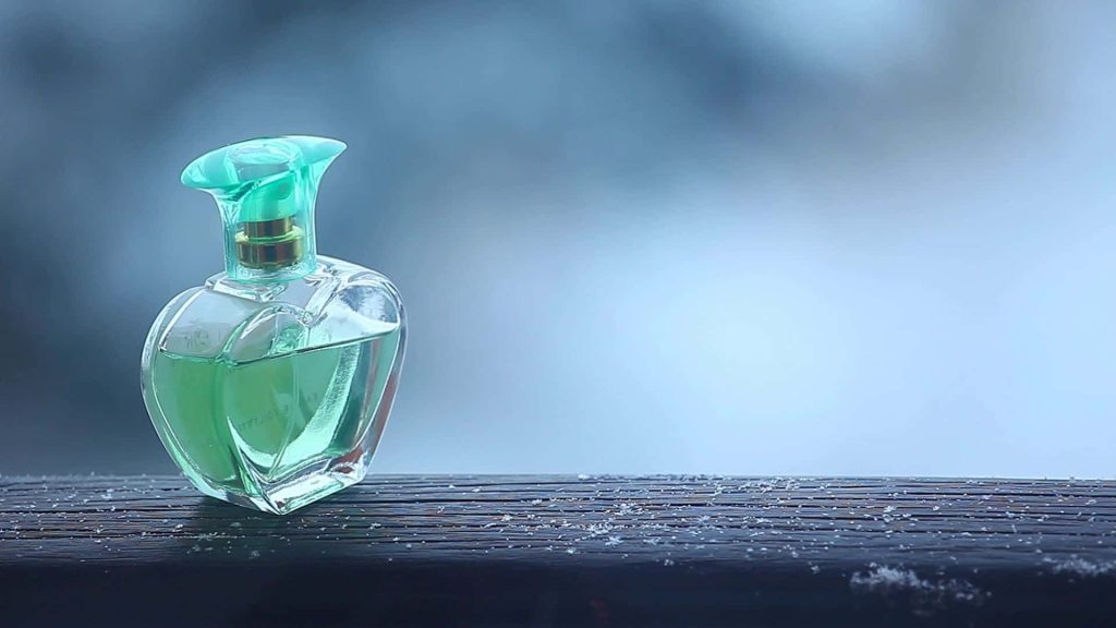 Heart-shaped perfume bottle with green liquid on frost-covered wood in soft winter background Wallpaper