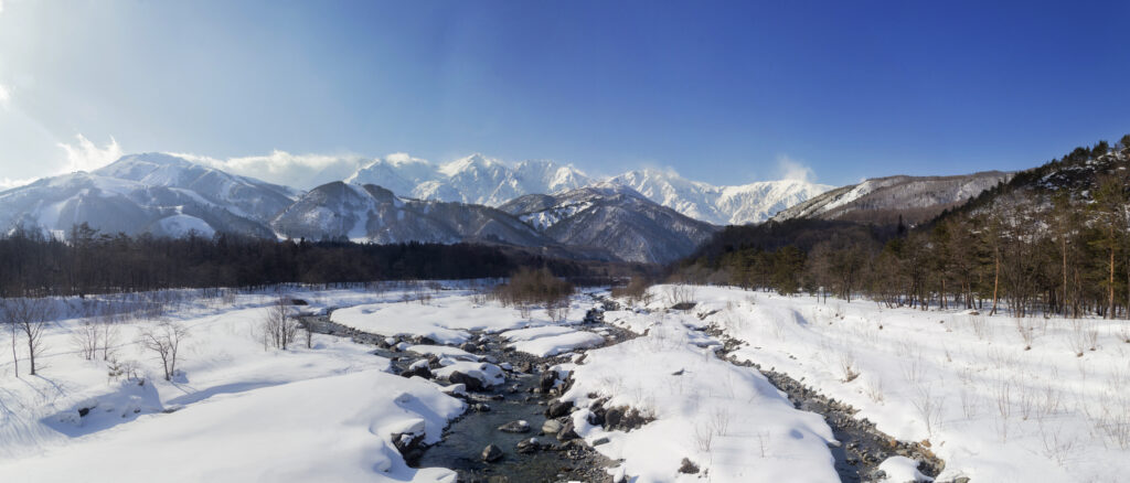 Snow-covered mountains and frosty valley with winding stream under clear blue sky wallpaper