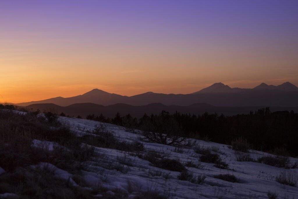 Serene winter landscape with snow slopes bushes mountain peaks sunset sky gradient wallpaper background