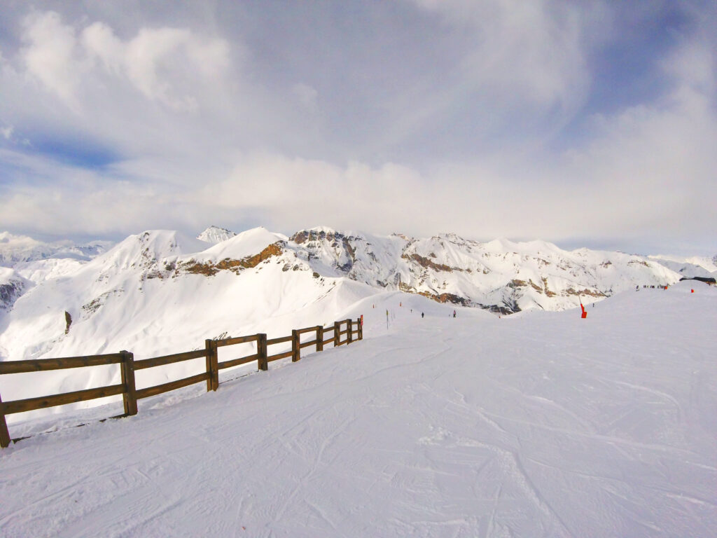 Snow-covered alpine mountains with wooden fence under partly cloudy sky winter landscape wallpaper