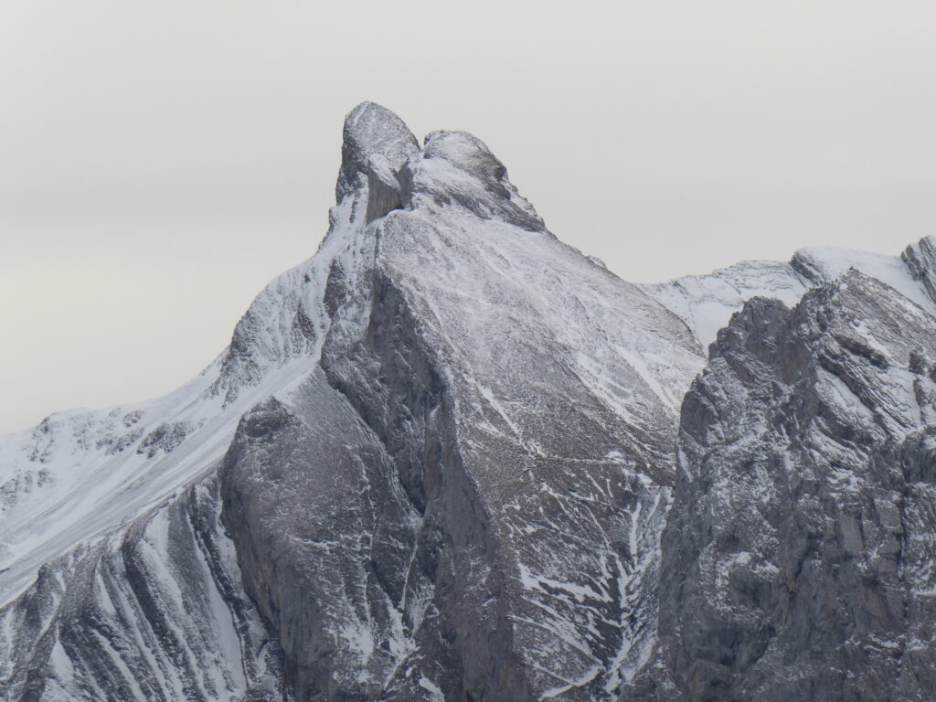 Dramatic snow dusted mountain peak with rugged rocks in serene gray winter landscape wallpaper