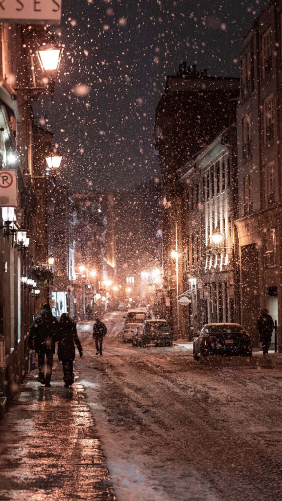 Serene Winter Night: People Walking on Snowy Street Wallpaper