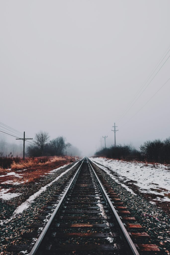 Snowy winter railway with misty tracks and bare trees in calm minimalist landscape background Wallpaper